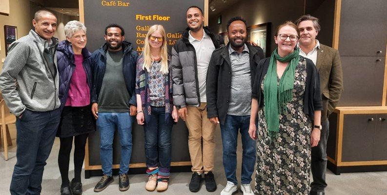A group of staff from global and public health at Brighton and Sussex medical school stood together in front of a door at the Towner gallery in Eastbourne