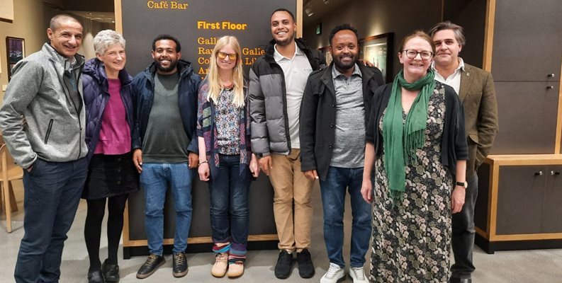 A group of staff from global and public health at Brighton and Sussex medical school stood together in front of a door at the Towner gallery in Eastbourne