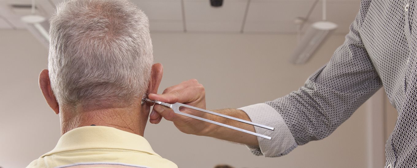 Teacher looks at back of male patient educator's head, using a metal tool