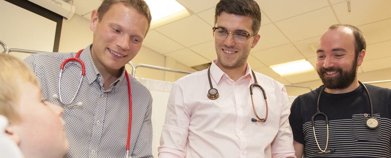 Male teacher and student doctor with a child patient