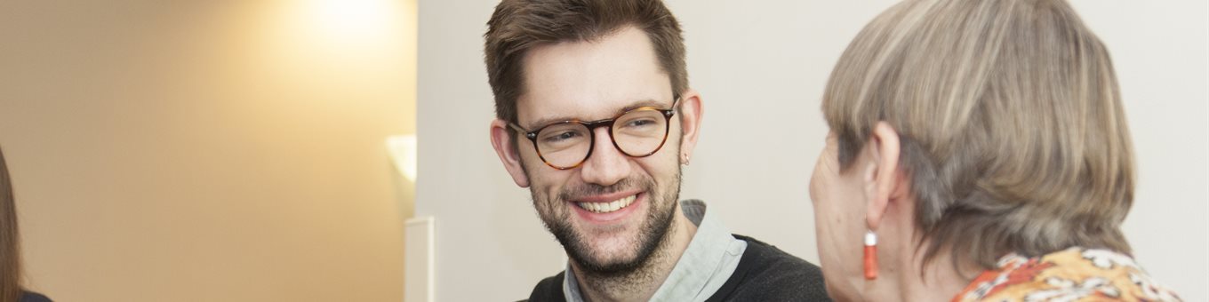 A male medical student smiling and talking with an elderly patient