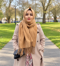 A portrait photo of Sultana Akther Suma, BSMS MRes student, standing in a park on a bright day, smiling towards the camera
