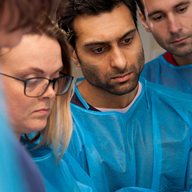 Students in blue gowns in dissection room