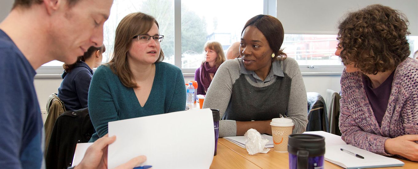 Dementia students in a seminar, sitting around a table reading papers and talking