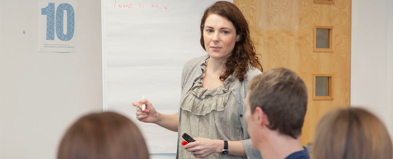 Teacher leading a Dementia class, at a whiteboard, about to write something