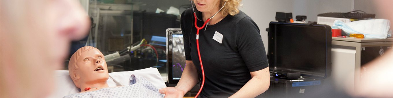 student with dummy patient in a simulation room