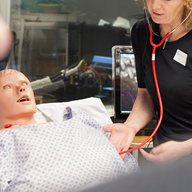 A student uses a stethoscope on a patient simulator