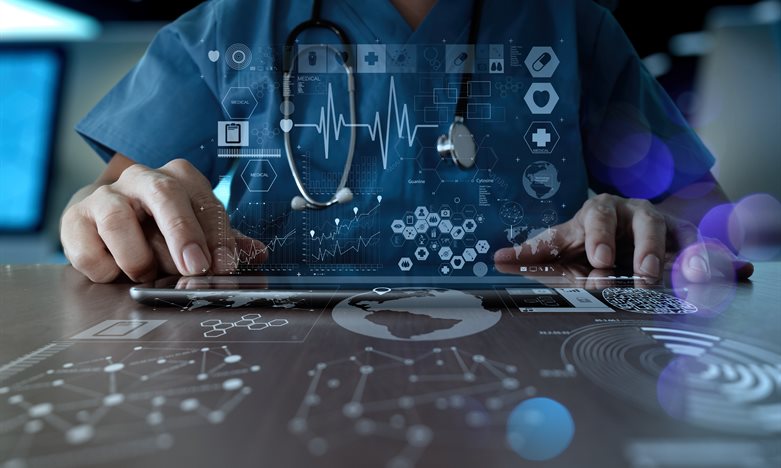 Medical professional sitting at a table with graphics and images representing medical data scattered across them