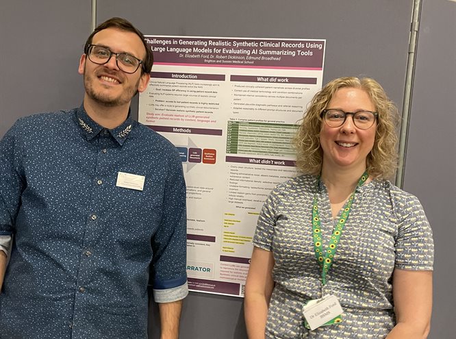 Liz and Rob stood either side of a poster smiling
