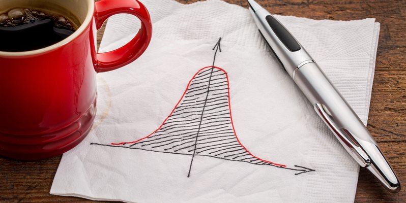 A red coffee mug, napkin with statistical drawing and a pen on a brown table