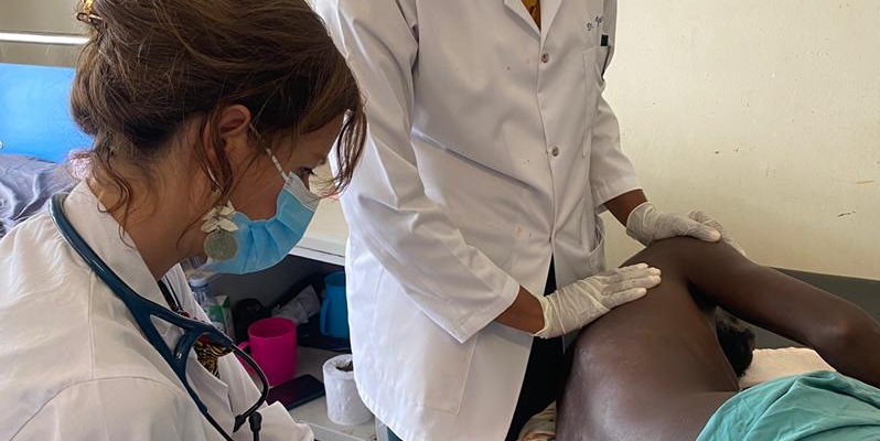 Two nurses treating a patient with am injection in a clinical setting