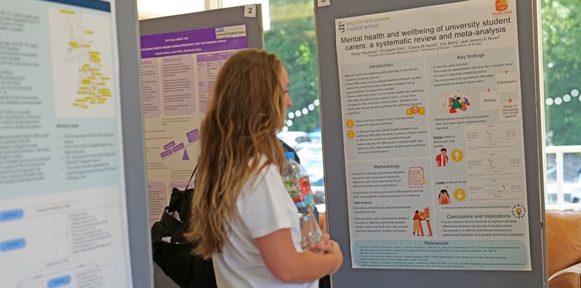 Someone stood in a room in front of a large display board with a poster on it