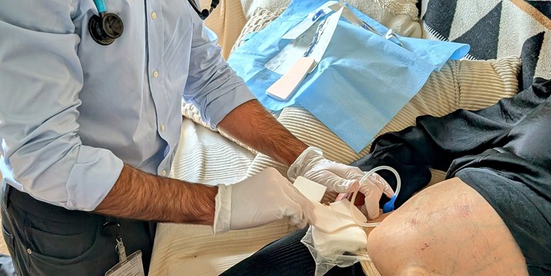 A doctor doing a surgical drain on a patient at home