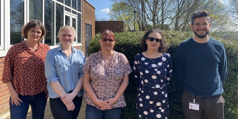 A group of people from the REDUCe2 team outside a building on a sunny day