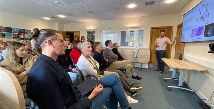 People sat in a room together facing the front listening to a presentation