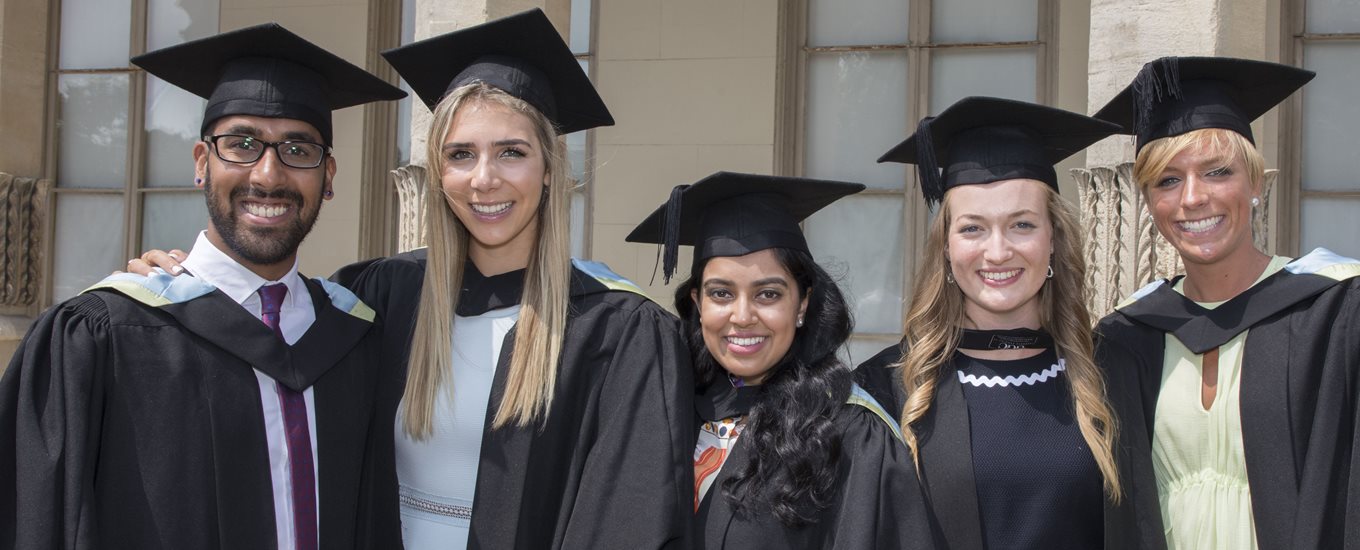 Three smiling students at graduation outside Brighton Pavilion