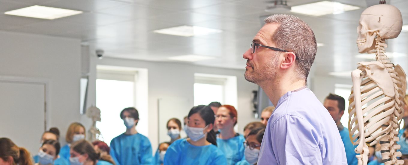 A doctor and students watching a talk in an anatomy lab