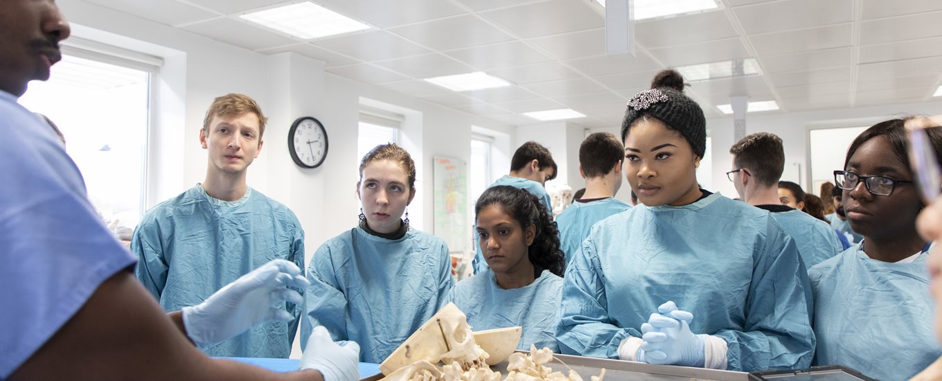 A group of gowned-up students standing in a dissection session