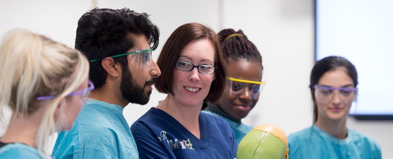 Students in blue gowns in anatomy suite with Prof Claire Smith