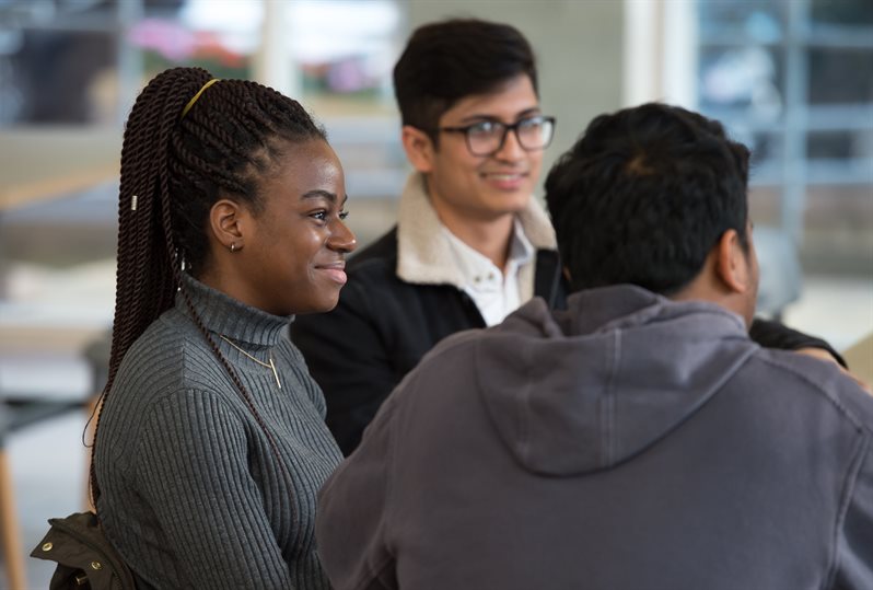 Three students sitting in cafe smiling