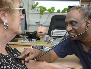 A patient being examined by a doctor in blue scrubs with a stethoscope