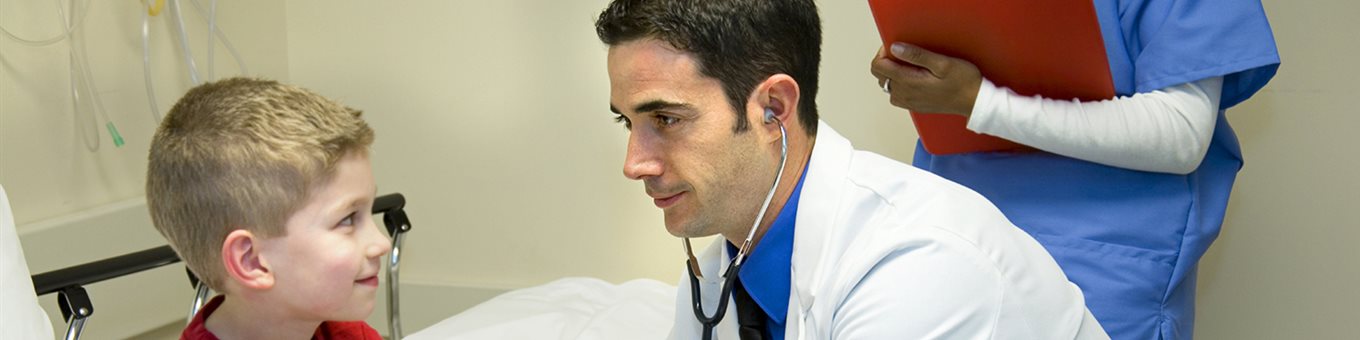 A doctor in a white lab coat using a stethoscope on a young patient