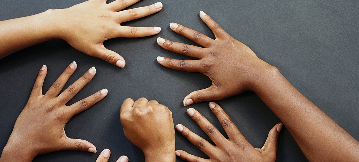 Several pairs of hands placed on a grey surface
