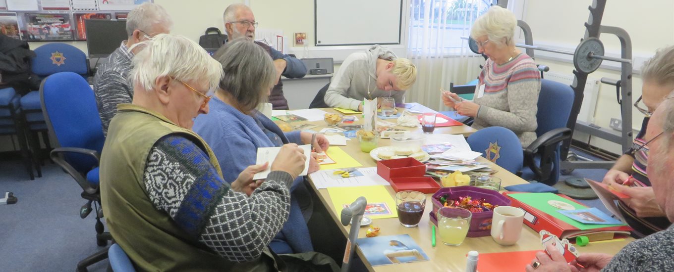four people sitting around a table taking part in a craft project, part of our improve fund