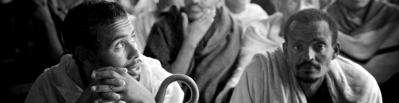 A black and white photo of people waiting in a medial centre. Image credited to Alex Kumar