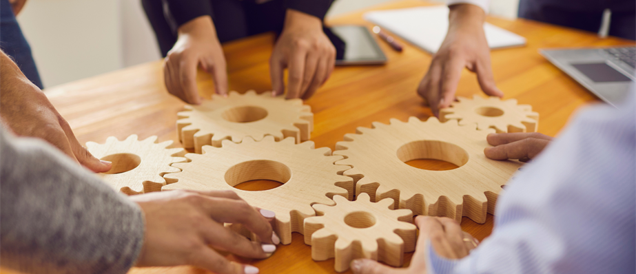 People sat round a table holding onto wooden cogs