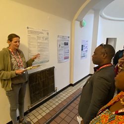 Global health students at a talk in a room with posters on the wall