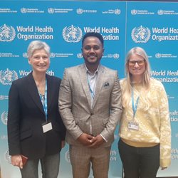 Gai Gem and Kibur from the global health team at BSMS pictured at a world health organization event in April 2023. They are stood in front of a blue board with the WHO logo on it.