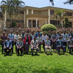 A group of people in two rows sat outside a hotel on a sunny day in Rwanda