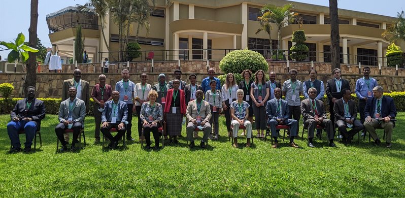 A group of people in two rows sat outside a hotel on a sunny day in Rwanda