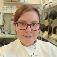A head and shoulders shot of Laura Steege in a white lab coat in a lab setting
