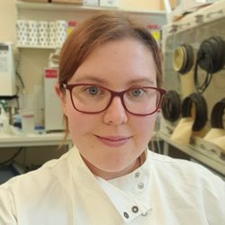 A head and shoulders shot of Laura Steege in a white lab coat in a lab setting