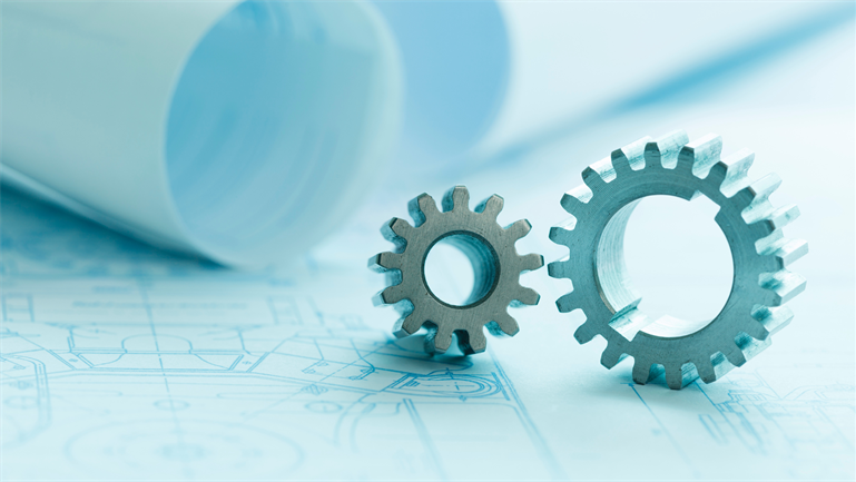 Two cogs sitting on a table with sheets of card behind them