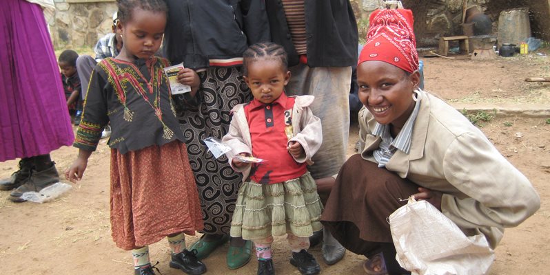 A women and two children pictured together on a clay path in Kenya