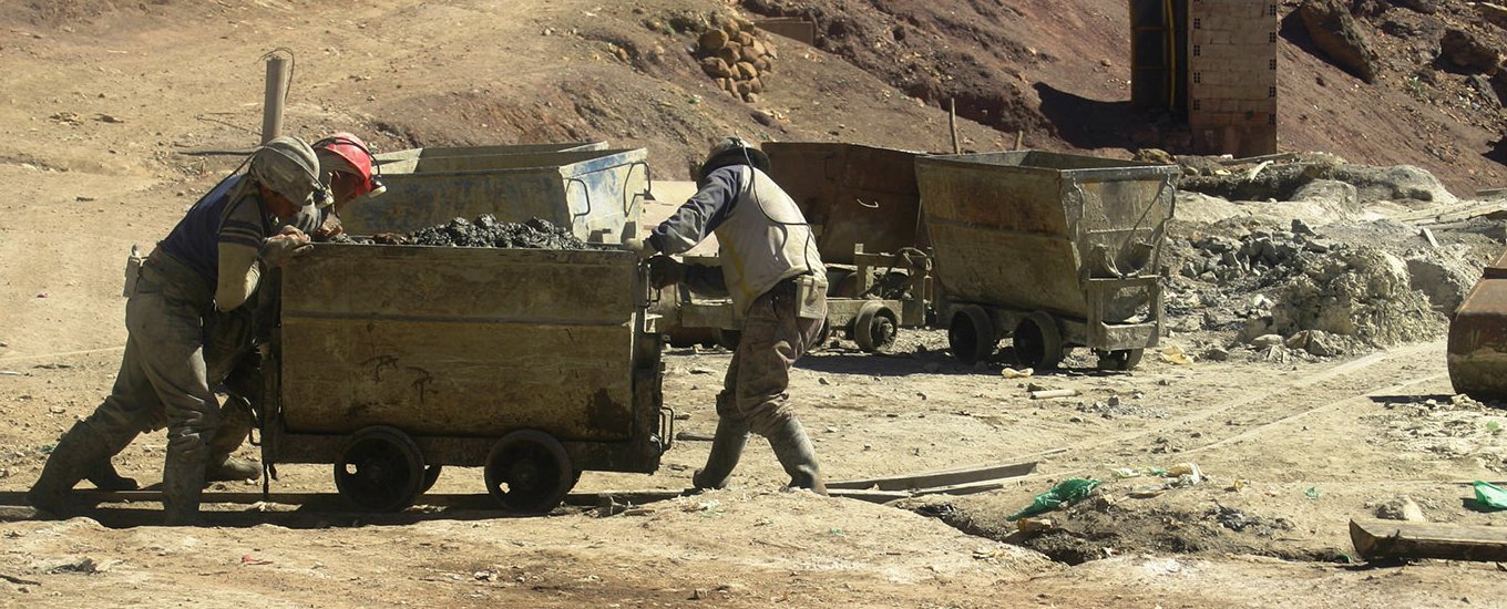 Two workers on the road pushing a coal cart