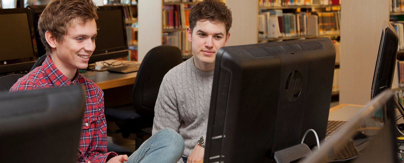 Two male students looking at a computer screen in the library