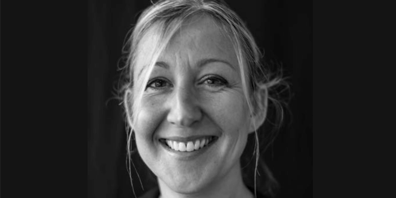 A black and white photo of Carrie Llewellyn from BSMS, smiling against a black background