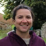 A head and shoulders photo of Clea Tanner outside in a purple coat