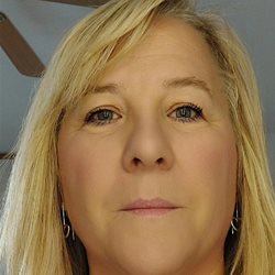 A head and shoulders shot of a woman with blond hair looking into the camera and smiling