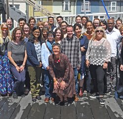 A group of people standing and sitting together on a decking area outside smiling at the camera