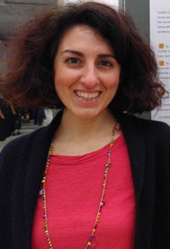 A profile photo of Lavinia Bertini, wearing a black and pink top next to a poster on a display board