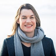 A women pictured wearing a scarf and jumper smiling at the camera