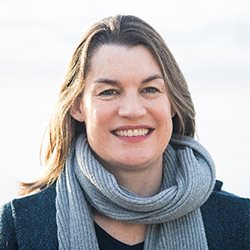 A women pictured wearing a scarf and jumper smiling at the camera