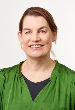 A head and shoulders image of Lisa Page in a green top in front of a white wall