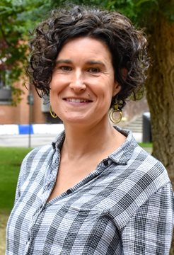 A head and shoulders photo of Maya Semrau, taken outside in front of a green leafy tree