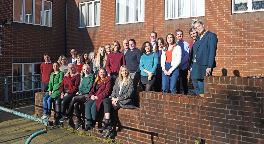 Image of neuroscience team stood and sat in front of building